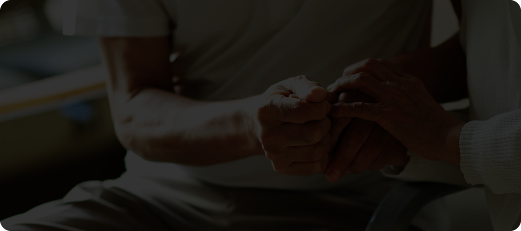 Close-up of two people sitting down facing each other grasping hands