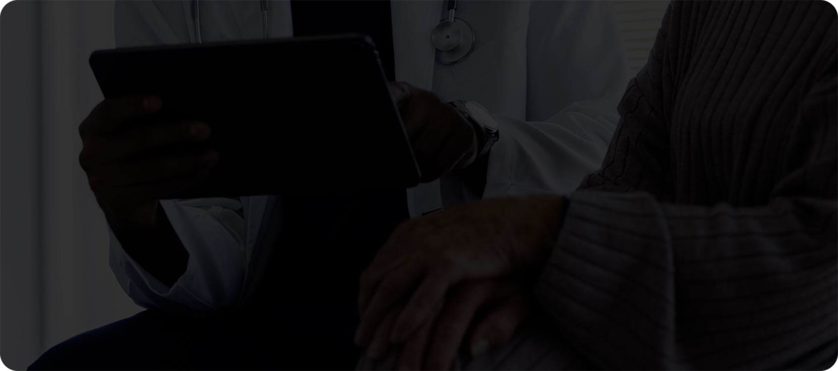 patient and a healthcare professional sitting beside each other looking at an iPad or similar device